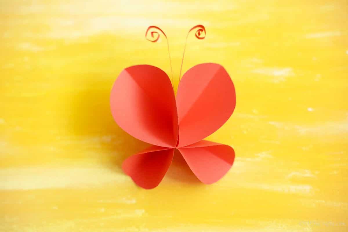 красная бумажная бабочка на желтой поверхности