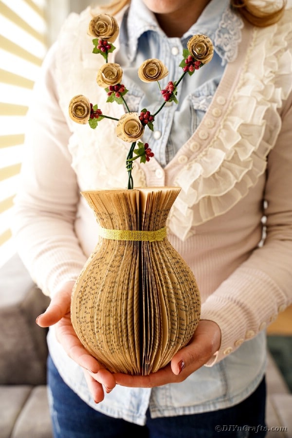 Женщина держит бумажную вазу с цветами
