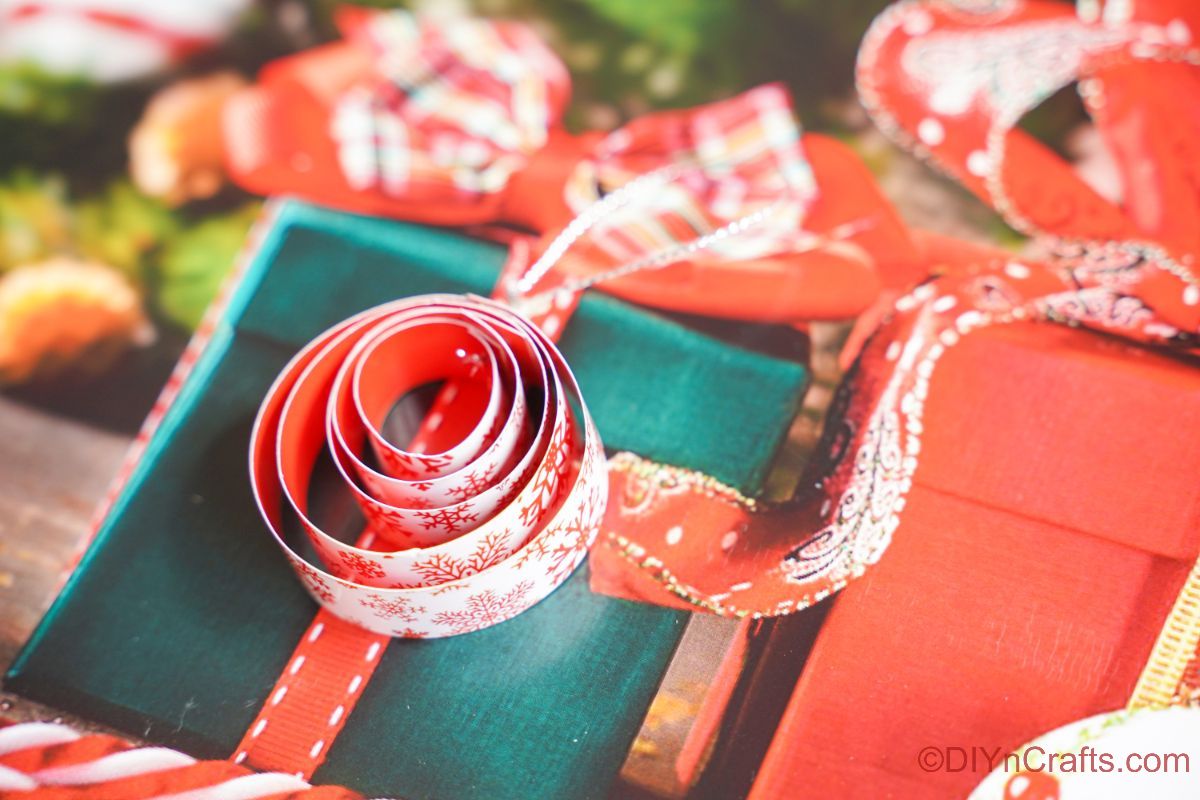 круглый орнамент из свернутой бумаги, сидящий поверх рождественского подарка, праздничной бумаги