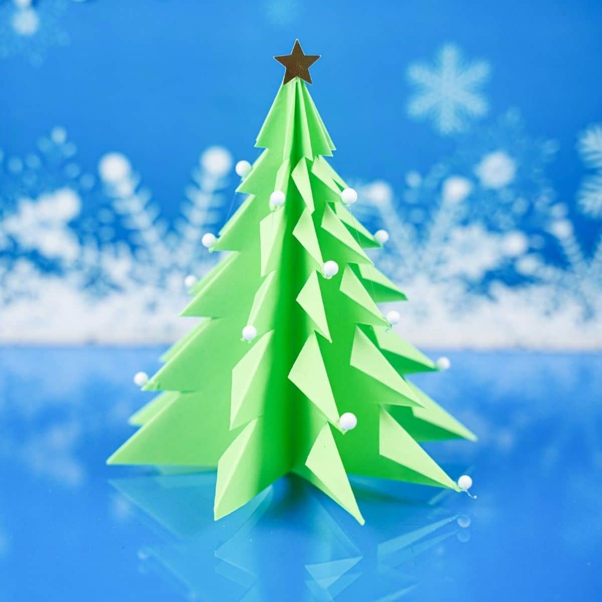 Синий снежный фон за зеленым бумажным деревом
