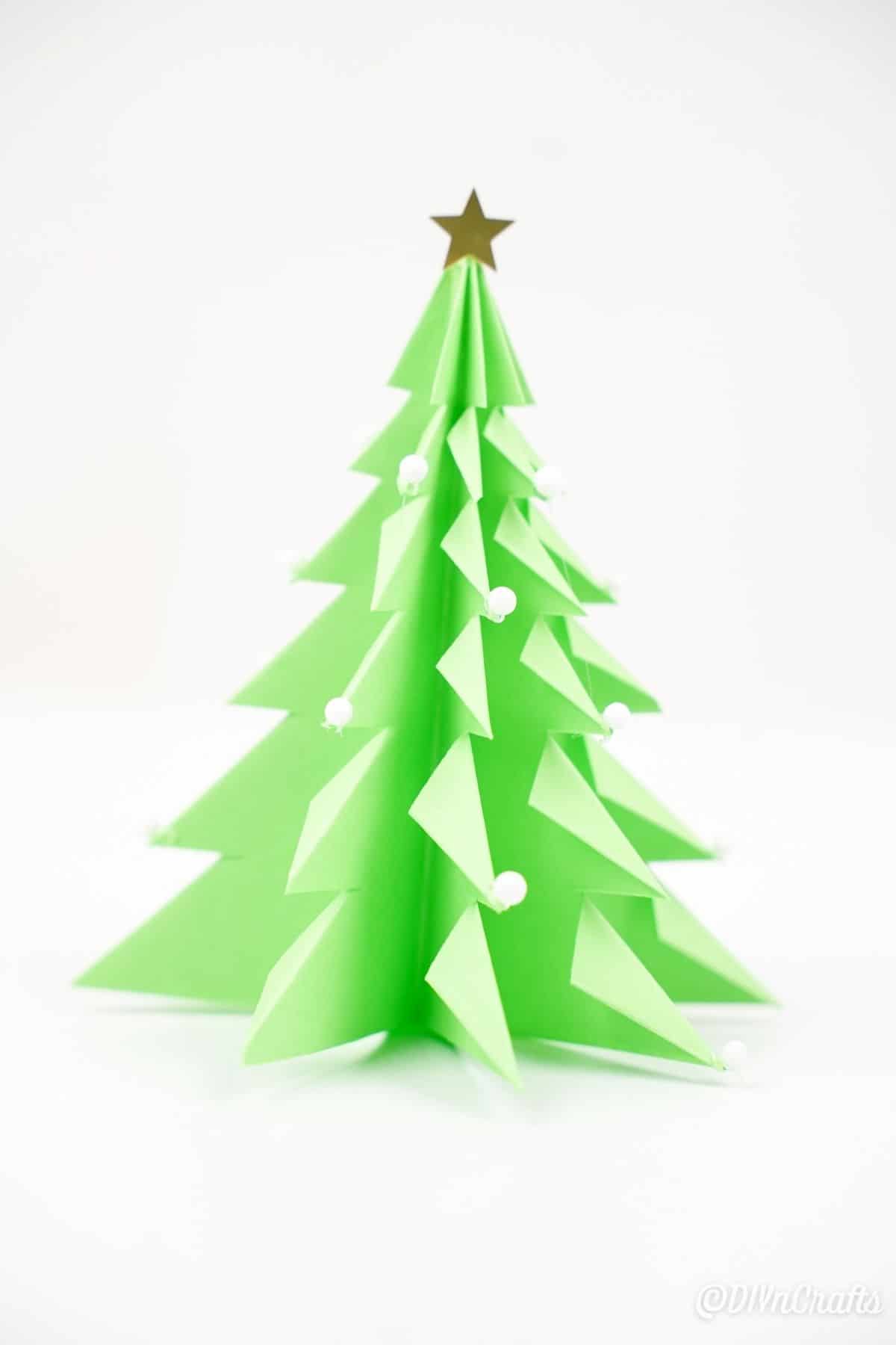 3d елка оригами в зеленой бумаге на белом столе