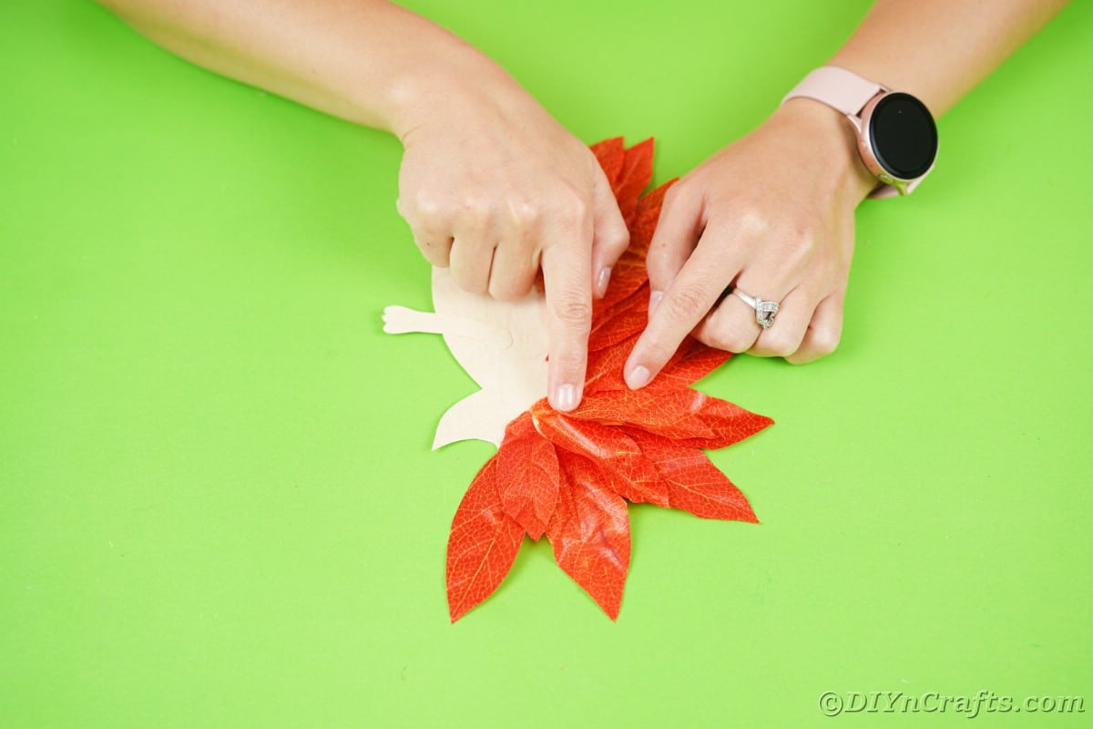 Руки держат поддельные листья на бумаге в форме ежа