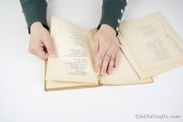 Женщина вырывает страницы из старой книги