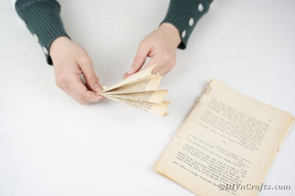 Женщина складывает страницу книги в форме веера