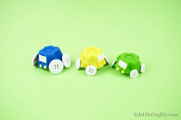 Синие желтые и зеленые игрушечные машинки на зеленой бумаге