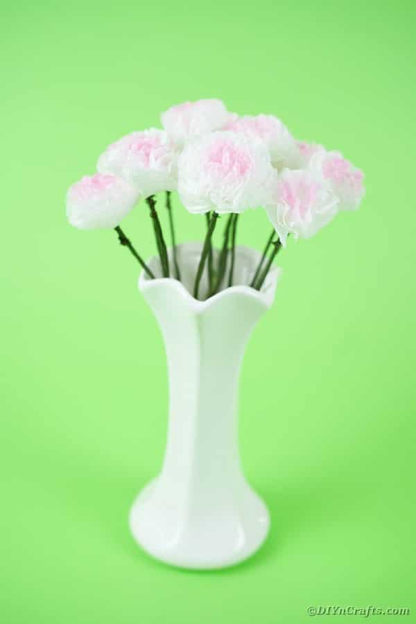 Бумажные цветы в белой вазе на зеленом фоне