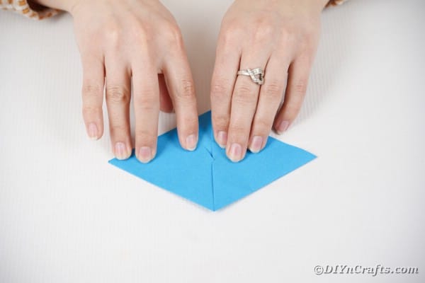 Руки складывают синюю бумагу