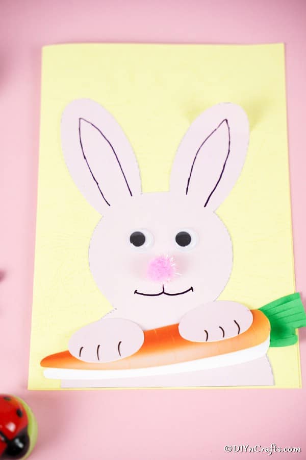 Распечатанная открытка с пасхальным кроликом на розовой поверхности
