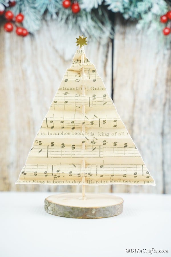 Рождественская елка из нотной бумаги на белом прилавке с праздничным декором на заднем плане