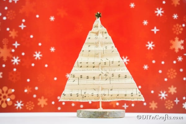 Рождественская елка из нотной бумаги на столе с красным праздничным фоном