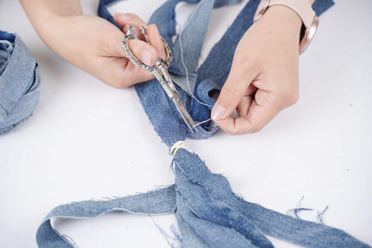 ножницы, обрезающие нить на джинсовой ткани