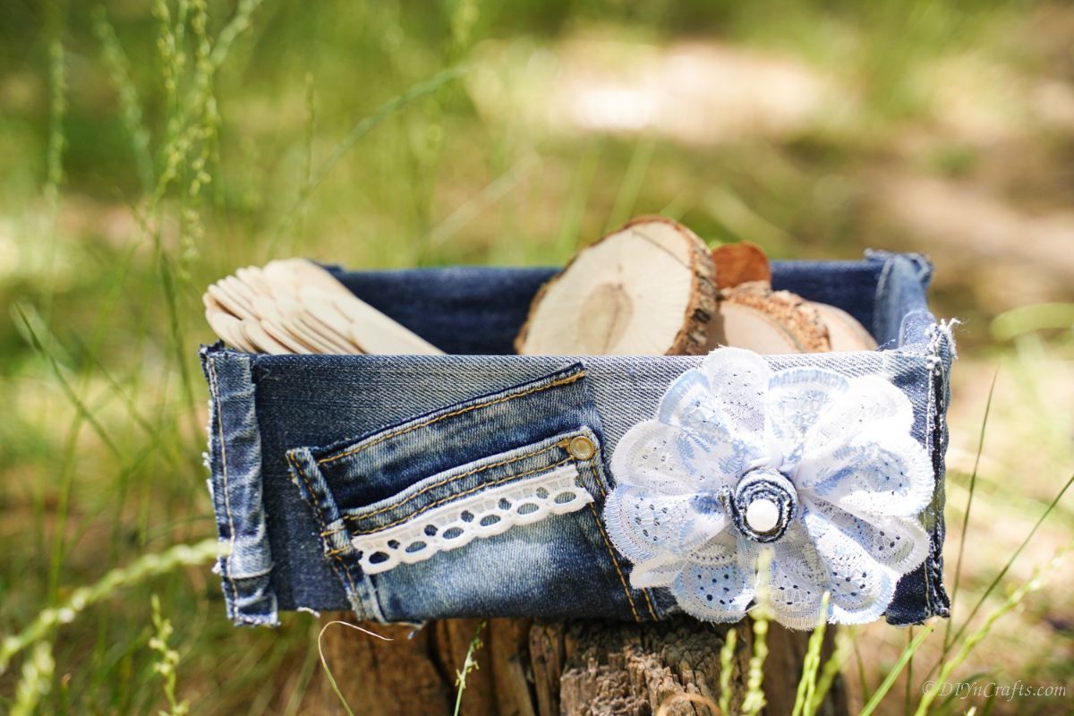 Коробка из джинсовой ткани на пне, наполненная ломтиками дерева и ремесленными палочками