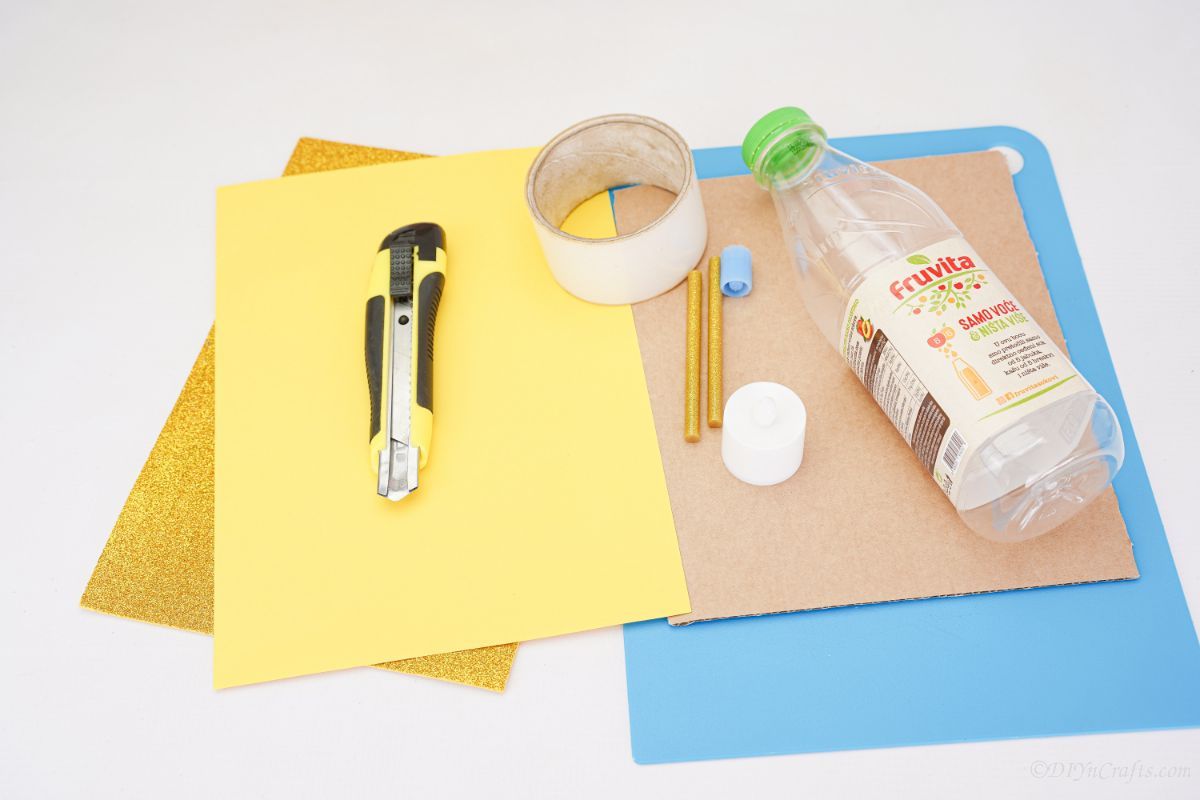ремесленный нож желтая бумага и картон на столе с бутылкой
