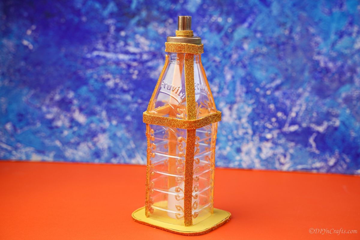 золотой фонарь из пластиковой бутылки на оранжевой бумаге