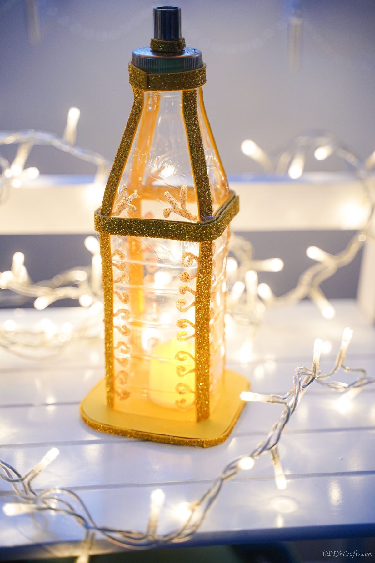 поддельный золотой фонарь на белом столе с рождественскими огнями