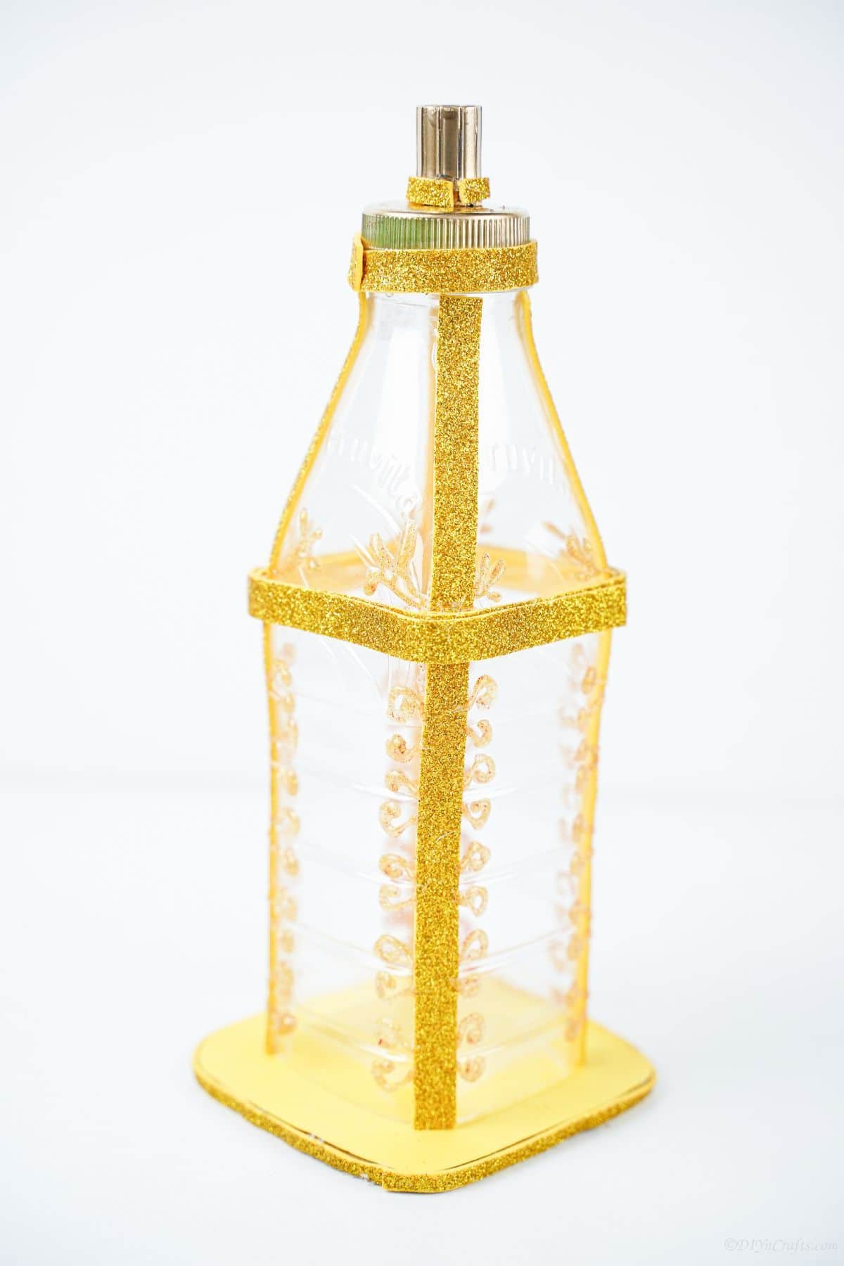 фонарь из пластиковой бутылки с золотой краской на белом столе